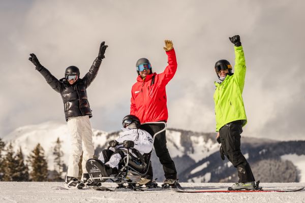 Photo of people in Challenge Aspen hanging out in the snow smiling and laughing.